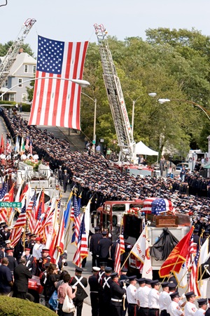 Thousands of firefighters from around the country line the street as fire engine bearing the casket of Paul Cahill is carried away from Holy Name Church in West Roxbury, Mass. Cardinal Sean P. O’Malley presided at the Sept. 6 funeral Mass for the fallen Boston firefighter.  Pilot photo/ Gregory L. Tracy     