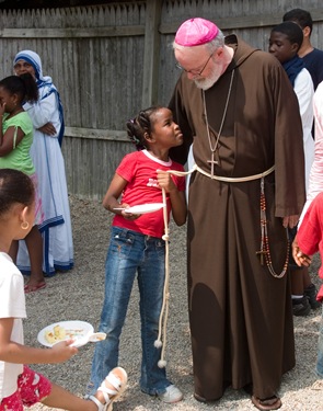  Jennifer Metybier, 8, displays an interest in Archbishop O’Malley’s cincture during picnic at the Missionary of Charities convent in Dochester July 19.  The archbishop spent the morning visiting with the children and volunteers of a day camp program run by the sisters for the mostly immigrant children of the neighborhood. Earlier the archbishop had celebrated Mass for the group.  Pilot photo by Gregory L. Tracy