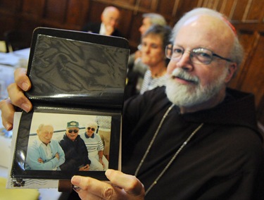 Cardinal Sean O'Malley poses with a gift (albums of photos including this photo of his parents) given to him following a service with the Serrans at the chapel of St. John's Seminary in Brighton, Mass., Friday, June 26, 2009. (Photo/Lisa Poole)