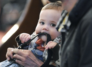 Gerard Sullivan, 8 months, of Boston, chews on a pocketbook strap as he sits with his grandmother Gerry Sparks, of Boston (not shown) during the Litergy of Good Friday with Seán Cardinal O’Malley at the Cathedral of the Holy Cross in Boston, Friday, April 2, 2010. (Photo/Lisa Poole)