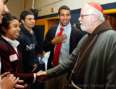 MARY SCHWALM/Staff photo Cardinal Sean P. O'Malley shakes hands with Notre Dame Cristo Rey High School student Natalya Villa as her friends Elie Azzi and Miguel Monclova, second right, look on in they gym at the school after participating in 10th anniversary mass of celebration and thanksgiving at St. Mary's Church in Lawrence.   10/9/13